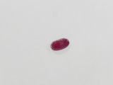 a single red stone sitting on top of a white surface