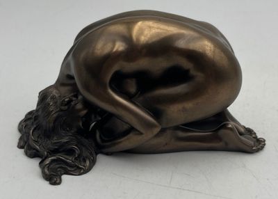 bronze sculpture of a woman laying on her back on a white surface