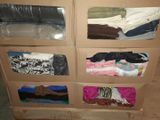 a lot of clothes in a cardboard box on the floor