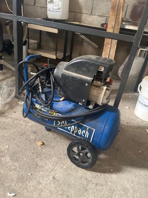 un compresseur d'air bleu posé sur un chariot dans un garage