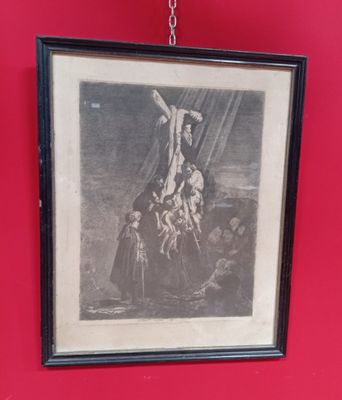 tableau accroché à un mur rouge représentant un homme sur une croix