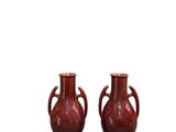 une paire de vases rouges munis d'anses de chaque côté d'un fond blanc