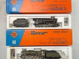 trois trains miniatures dans leurs boîtes, empilés les uns sur les autres sur une table