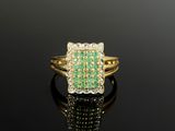 une bague en émeraude et diamant sur une surface noire