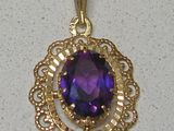 une image représentant un pendentif en or orné d'une pierre violette au centre