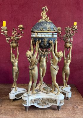 a clock that is sitting on a table with candles