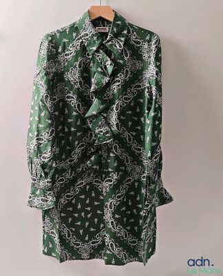 une photo d'une veste à motifs cachemire verts et blancs, suspendue à un cintre