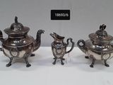two silver plated teapots with lids and handles on a white surface