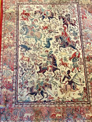 un tapis oriental posé sur un parquet, bordé d'une frange rouge