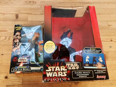Deux figurines de Star Wars sont posées dans une boîte sur une table en bois