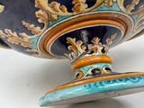 a blue and orange vase with a gold decoration on it
