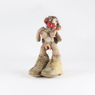 une petite statue représentant un clown assis sur une paire de chaussures