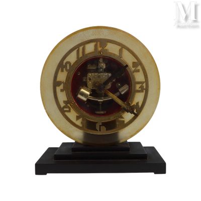 une horloge dorée posée sur un socle noir, sur fond blanc