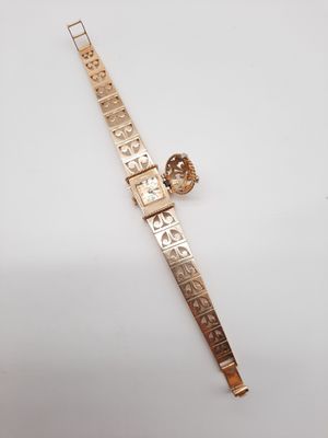 gros plan d'une montre en or sur une surface blanche