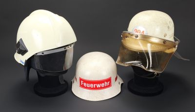 deux casques blancs et un casque blanc exposés sur une surface noire