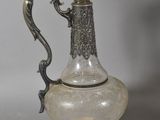 a silver and glass pitcher with a handle on a table