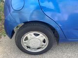 a blue car that has a flat tire on the side of the road