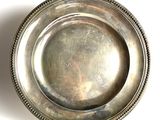 a silver plate with a beaded edge on a white surface