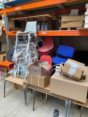 boxes and chairs are stacked on a table in a warehouse