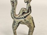 une ancienne figurine en bronze représentant une femme assise sur un chameau
