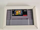 an old nintendo game in a white frame on a white table