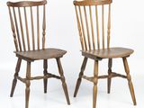 two wooden chairs sitting next to each other on a white surface