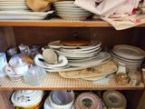 many plates and bowls stacked on a shelf in a cabinet
