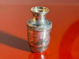 a small silver vase sitting on a red table