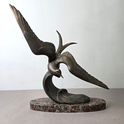 sculpture en bronze représentant un oiseau tenant un poisson dans son bec, posée sur un socle en marbre