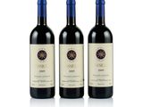 trois bouteilles de vin rouge posées l'une à côté de l'autre sur une surface blanche