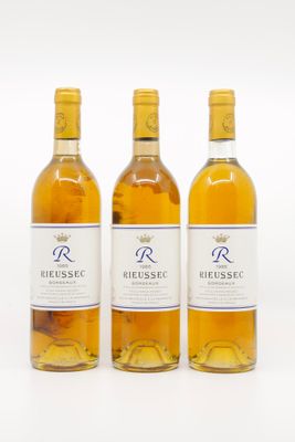 trois bouteilles de vin posées les unes à côté des autres sur une surface blanche