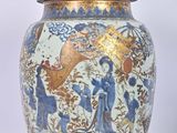 un vase bleu et or muni d'un couvercle, posé sur une surface blanche
