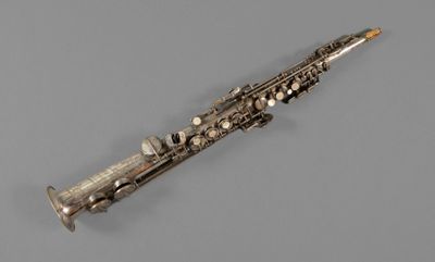 an antique silver plated saxophone on a gray background
