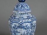a blue and white vase with a bird on top of it