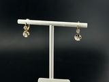 a pair of earrings on a stand with a price tag