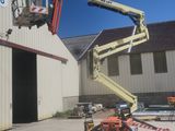 a picture of a man on a cherry picker in front of a building