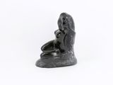 a black statue of a woman sitting on a rock