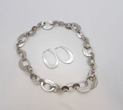 un gros plan sur un bracelet à chaîne en argent accompagné d'une paire de boucles d'oreilles