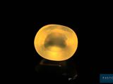a close up of a yellow glass ball on a black surface