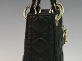 black quilted handbag with gold handles on a white surface