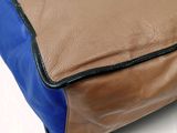 a brown and blue bag sitting on a white surface
