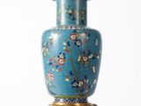 un vase bleu posé sur un socle, sur une surface blanche