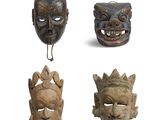 quatre masques en bois représentant différents visages sur fond blanc
