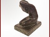 une statue en bronze représentant une femme assise sur un bloc de marbre