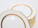 a stack of plates with gold rims on a white table