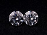 a pair of round cut diamonds on a black surface
