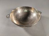 an old silver bowl with a handle on a white surface