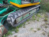 a green and yellow excavator that is sitting in the grass