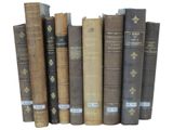 several old books are lined up in a row on a white surface