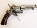un vieux revolver avec une poignée en bois sur une surface blanche